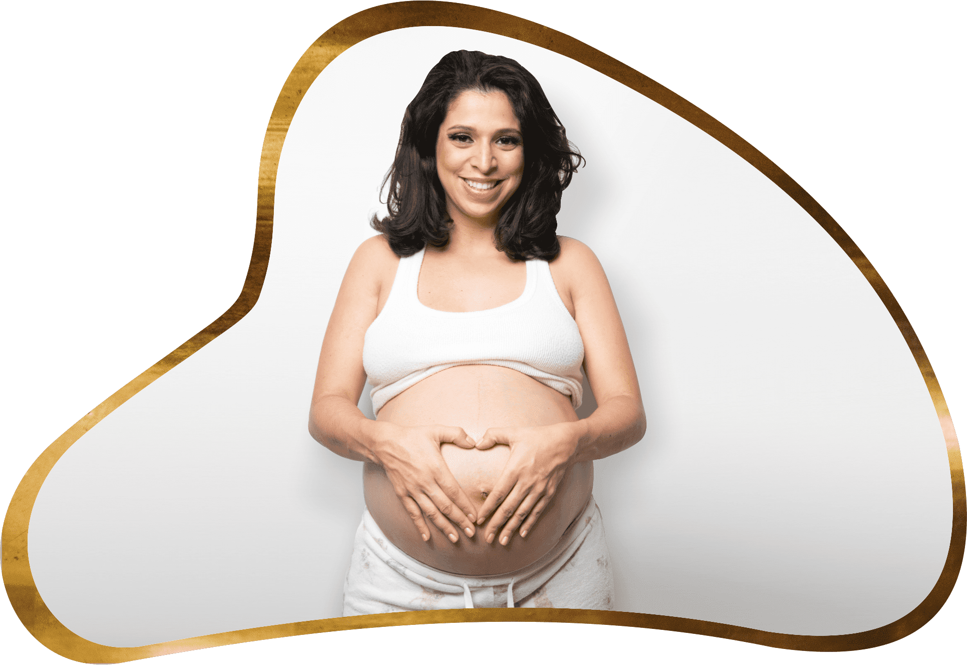 A pregnant woman holding her belly in front of a white wall.